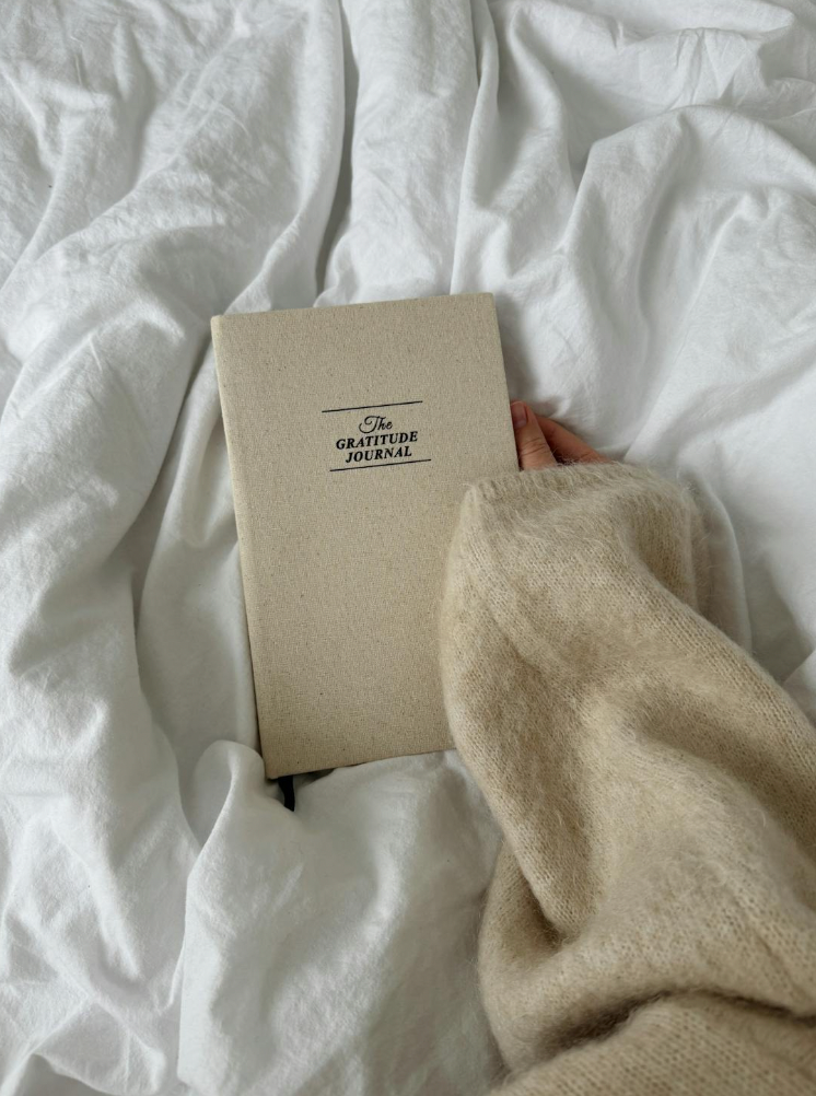 Journal abour gratitude in bed with person holding it